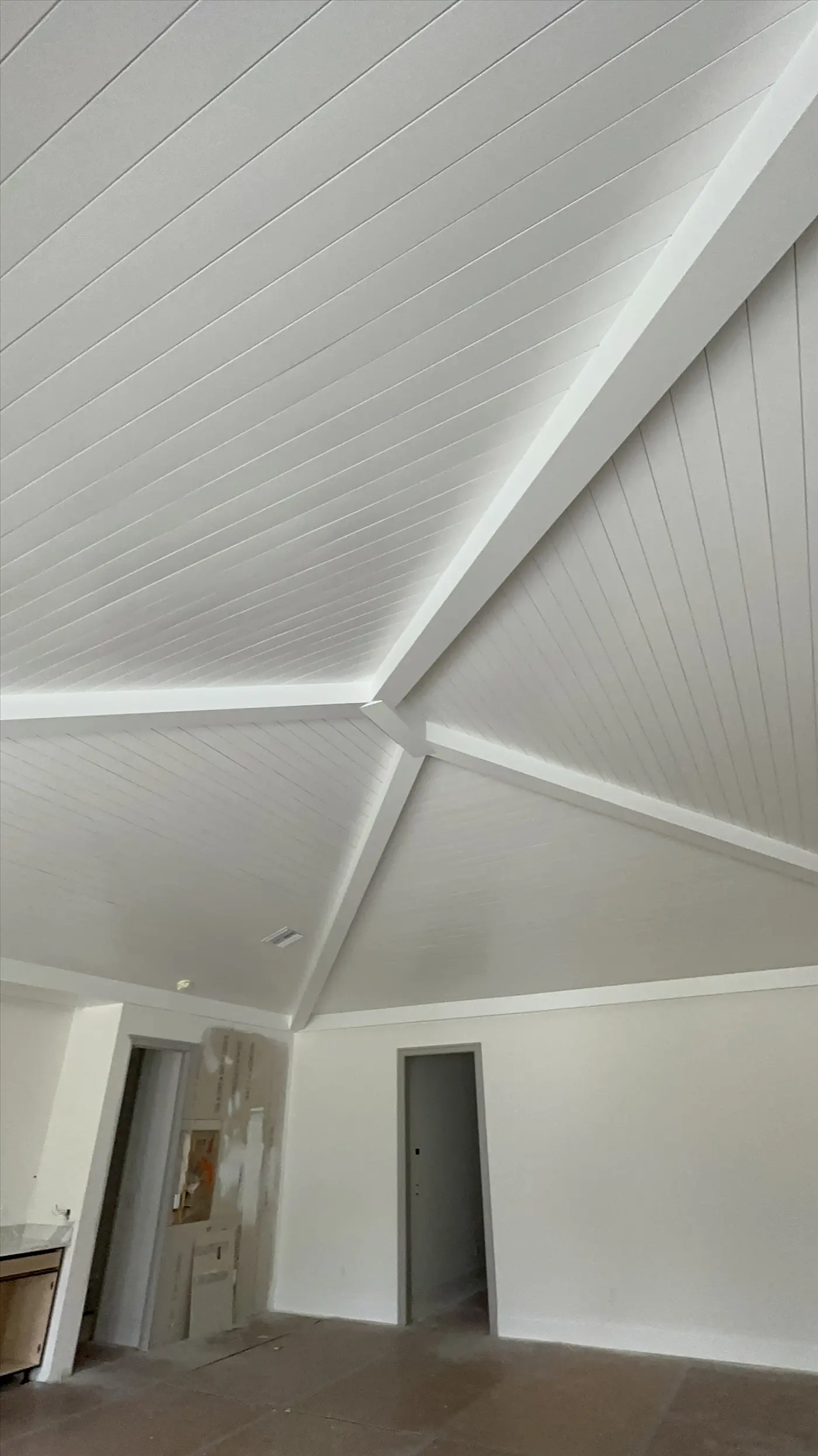 Vaulted shiplap ceiling with white painted beams and clean wall lines