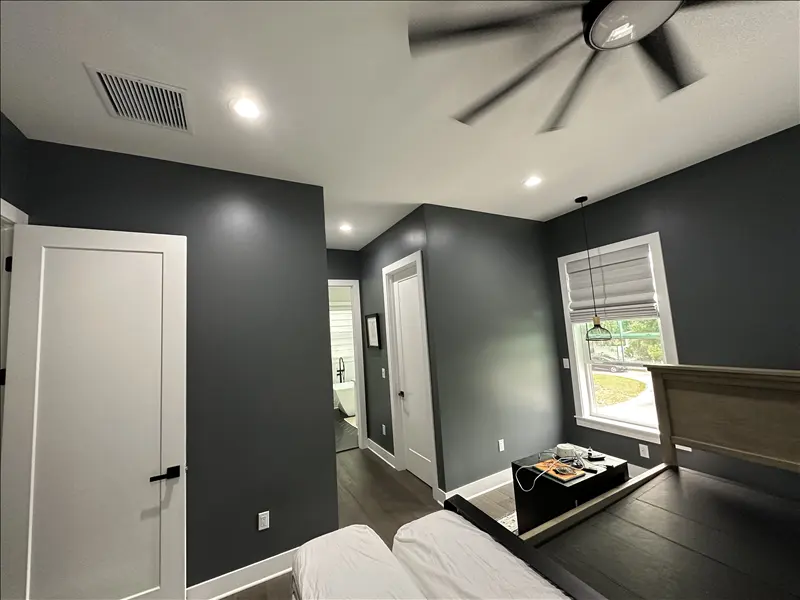 Bedroom with deep charcoal accent walls and crisp white trim and doors