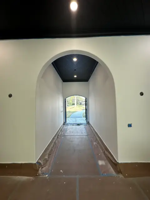 White arched hallway with a dark ceiling and a view to the entry