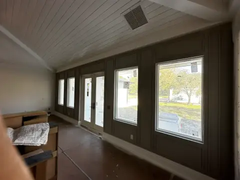 Room with dark painted wall paneling, white windows and a white shiplap ceiling